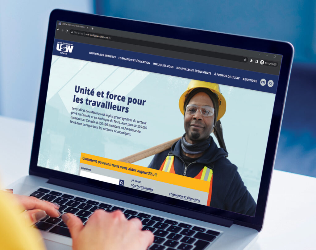 Hands are seen typing on a laptop keyboard with a window browser opened to the new USW website.