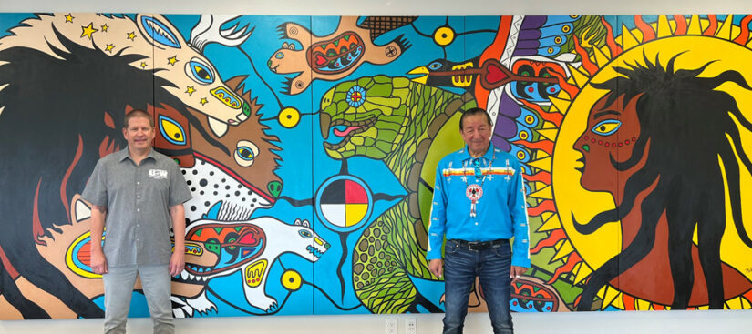 District 6 Director Myles Sullivan and Indigenous artist Philip Cote standing in front of a mural