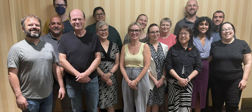 The image is of a group of 15 people, standing 