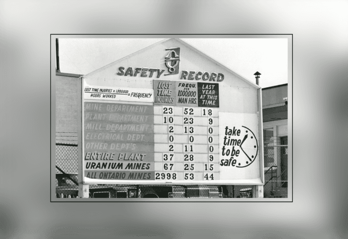 A black and white photo of a huge billboard showing records of injuries in a mine by department.