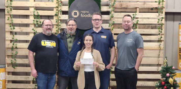 Five USW members taking a photo with a food bank representative. The rep is holding a cheque.