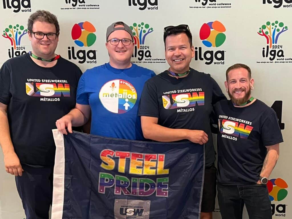 four men standing with the pride flag