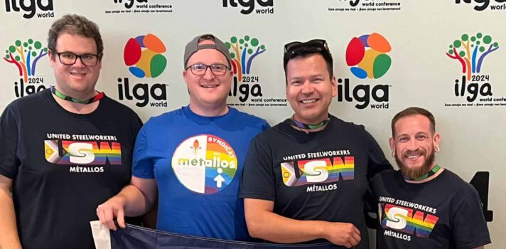 four men standing with the pride flag 