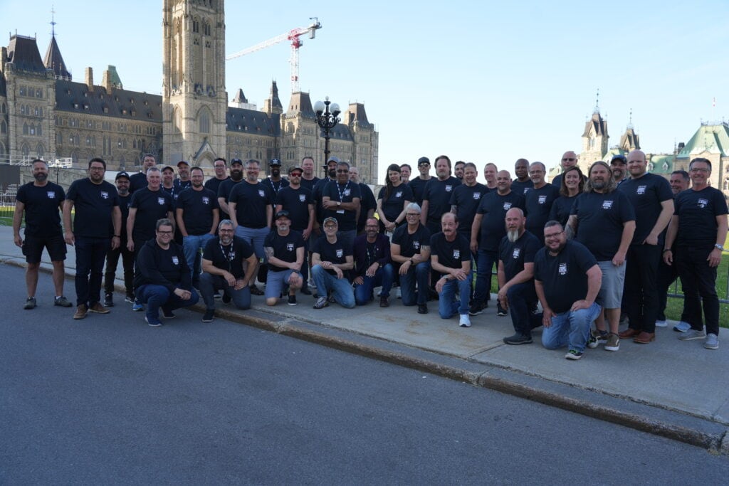 group of people standing in front of the parliament hill wearing bleu t-shirts