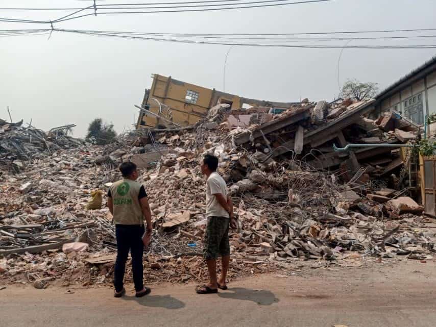 2 people standing and watching demolished buildings