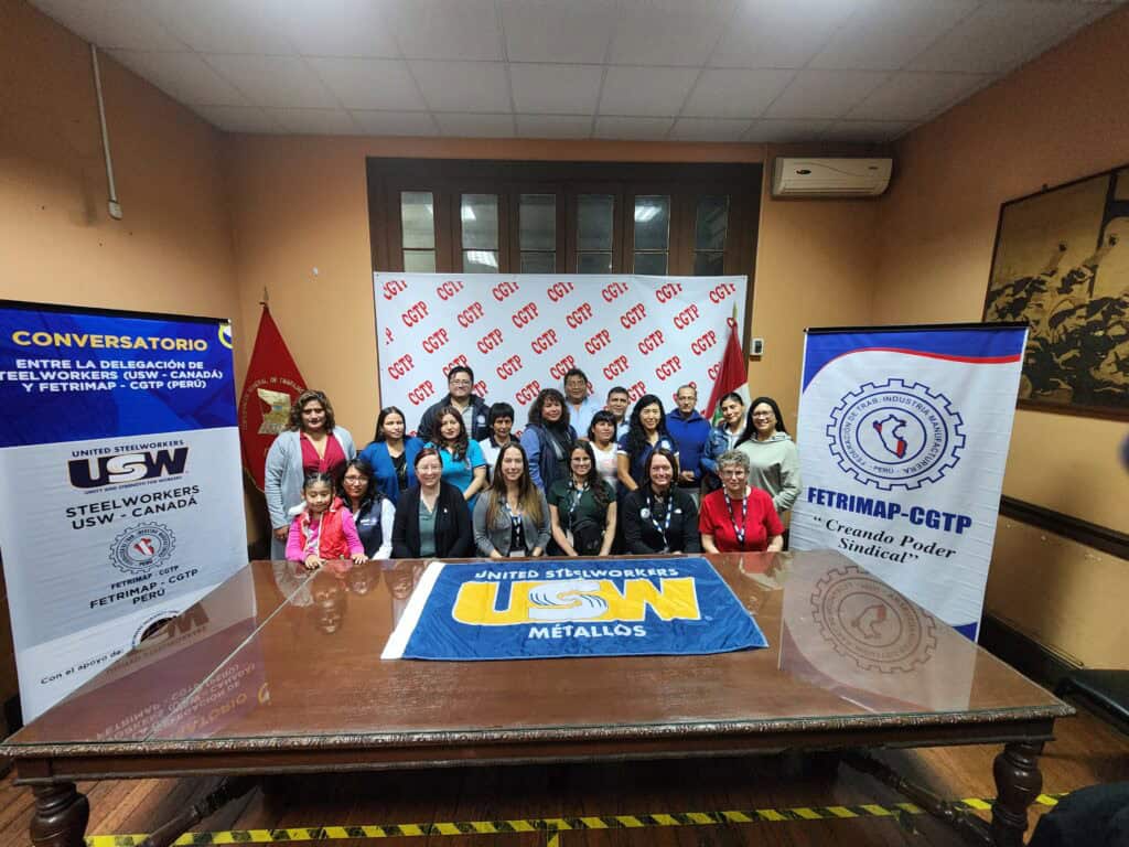 A group of people sitting behind a desk while taking a photo.