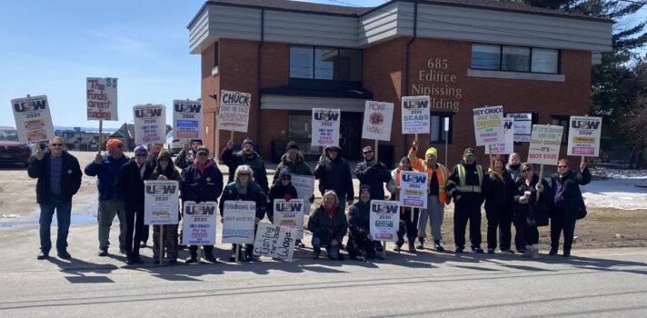 A group of people standing in front of a building with signs. 